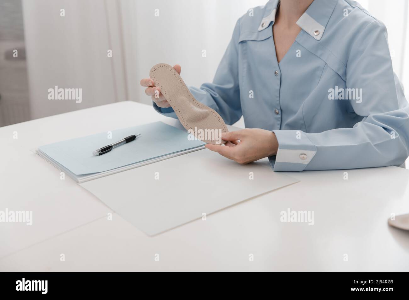 Doctor holding an insole while sitting at a table. Orthopedist tests the medical device. Orthopedic insoles. Foot care. Flat Feet Correction Stock Photo