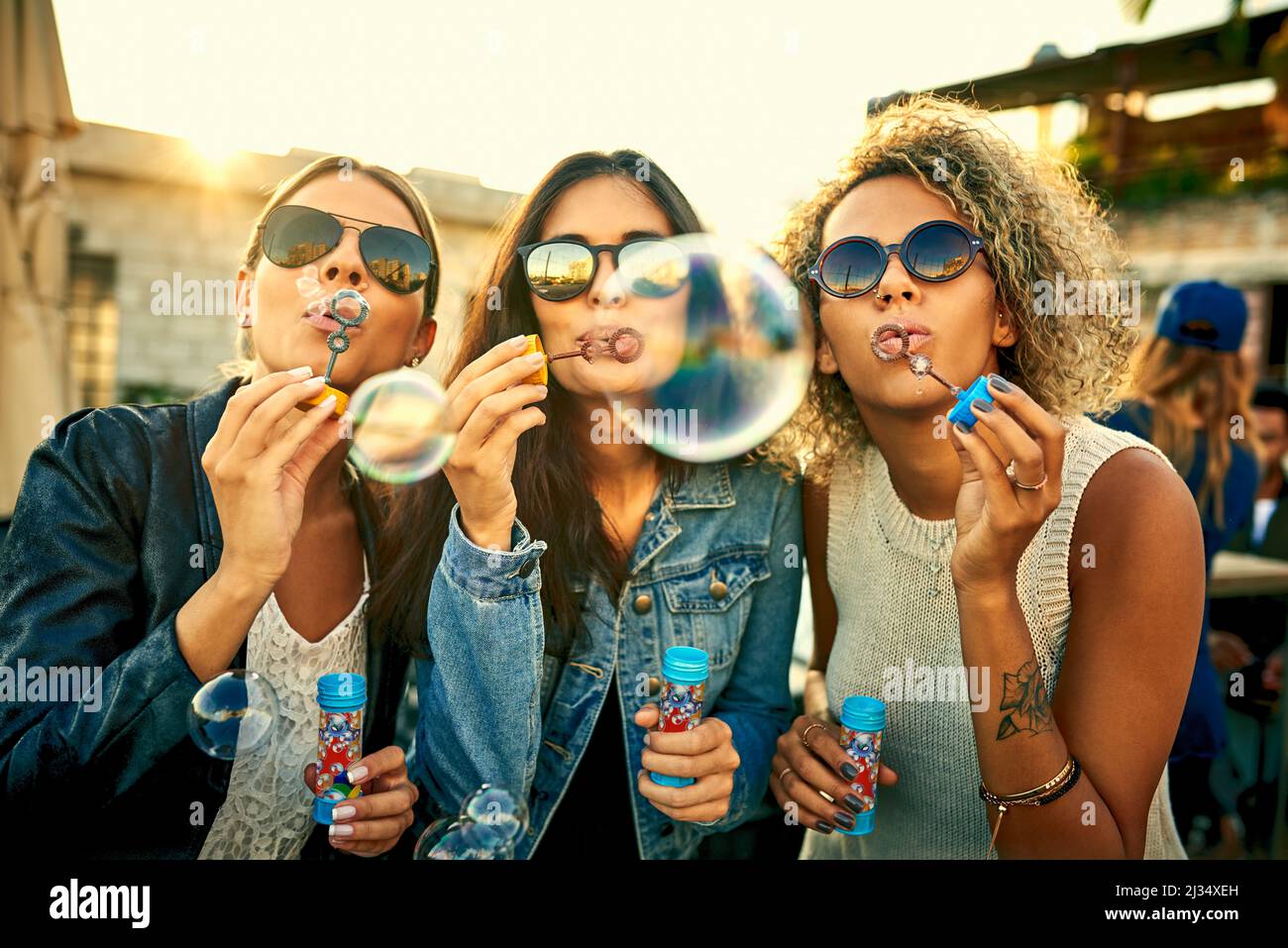 No moment spent blowing bubbles was ever wasted. Shot of a group of young women blowing bubbles together outdoors. Stock Photo
