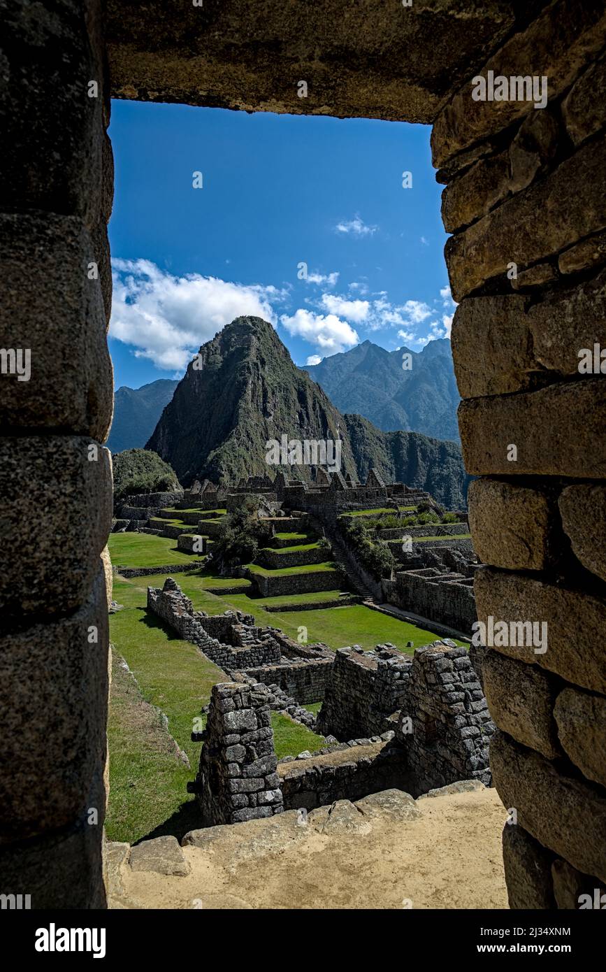 Machu Picchu throiugh ancient stone doorway looking onto farming terraces used by inca as temple and holy place. Stock Photo