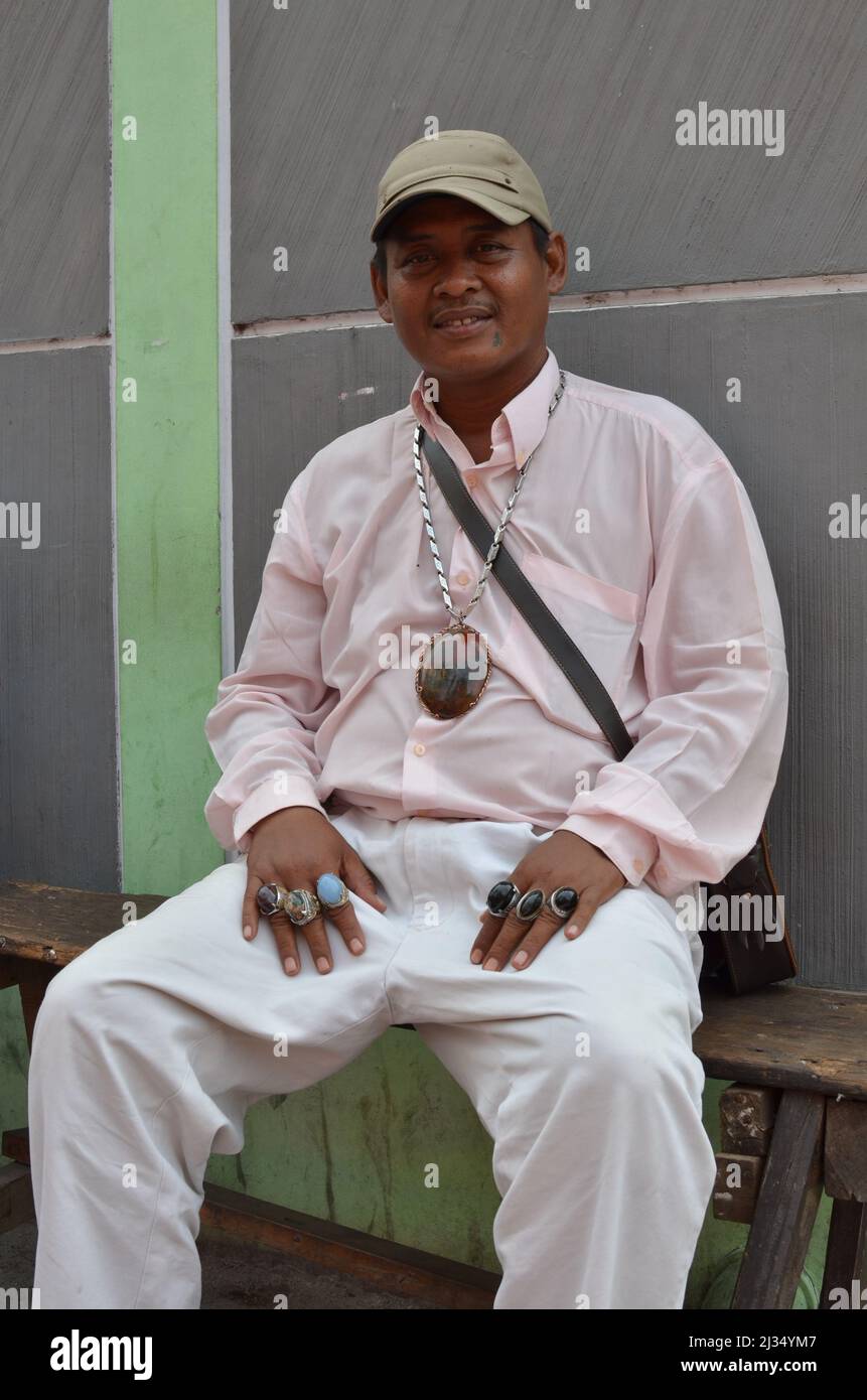 An Indonesian man sitting on the bench showing his hands with rings on every finger Stock Photo