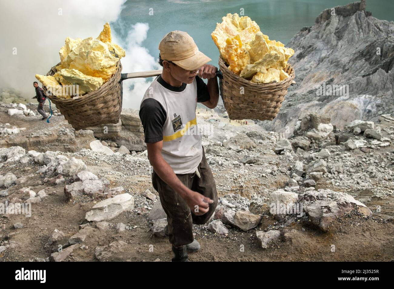 Porter carrying two baskets filled with sulfur from Ijen volcano crater, Java Island, Indonesia Stock Photo