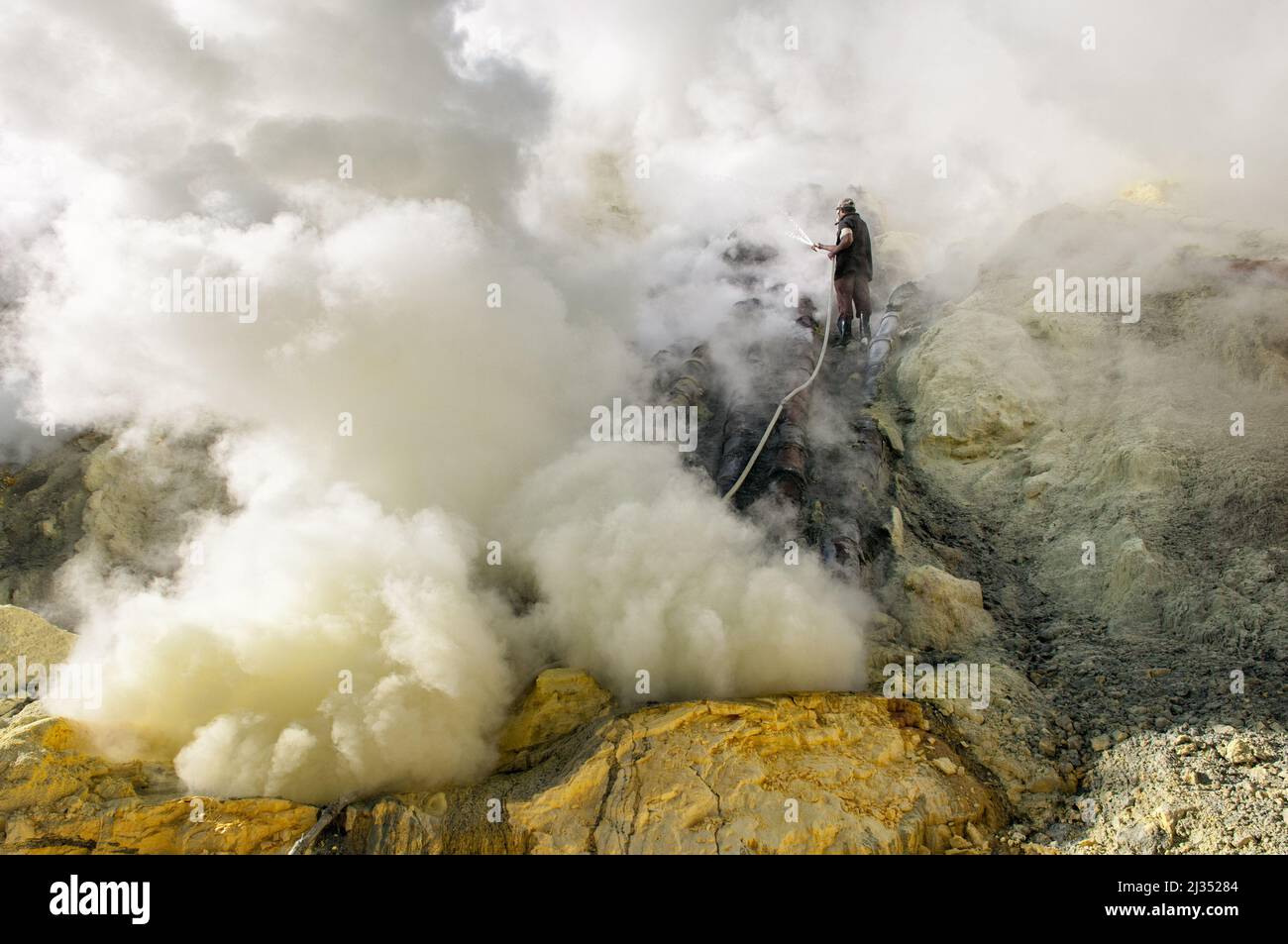 Sulfur miner cooling pipes inside the crater of Ijen volcano, Java island, Indonesia Stock Photo