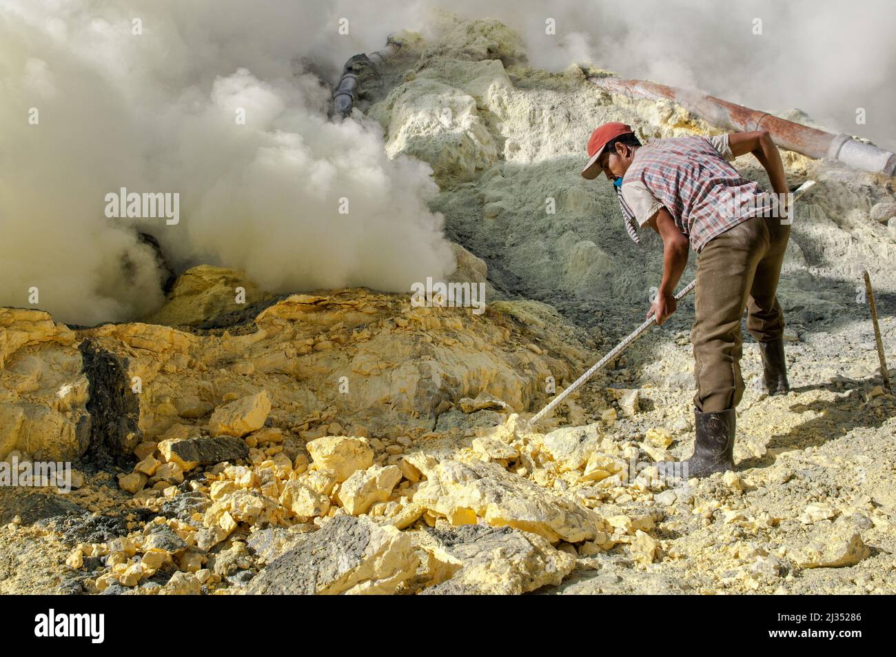 Miner extracting sulfur inside the crater of Ijen volcano, Java island, Indonesia Stock Photo