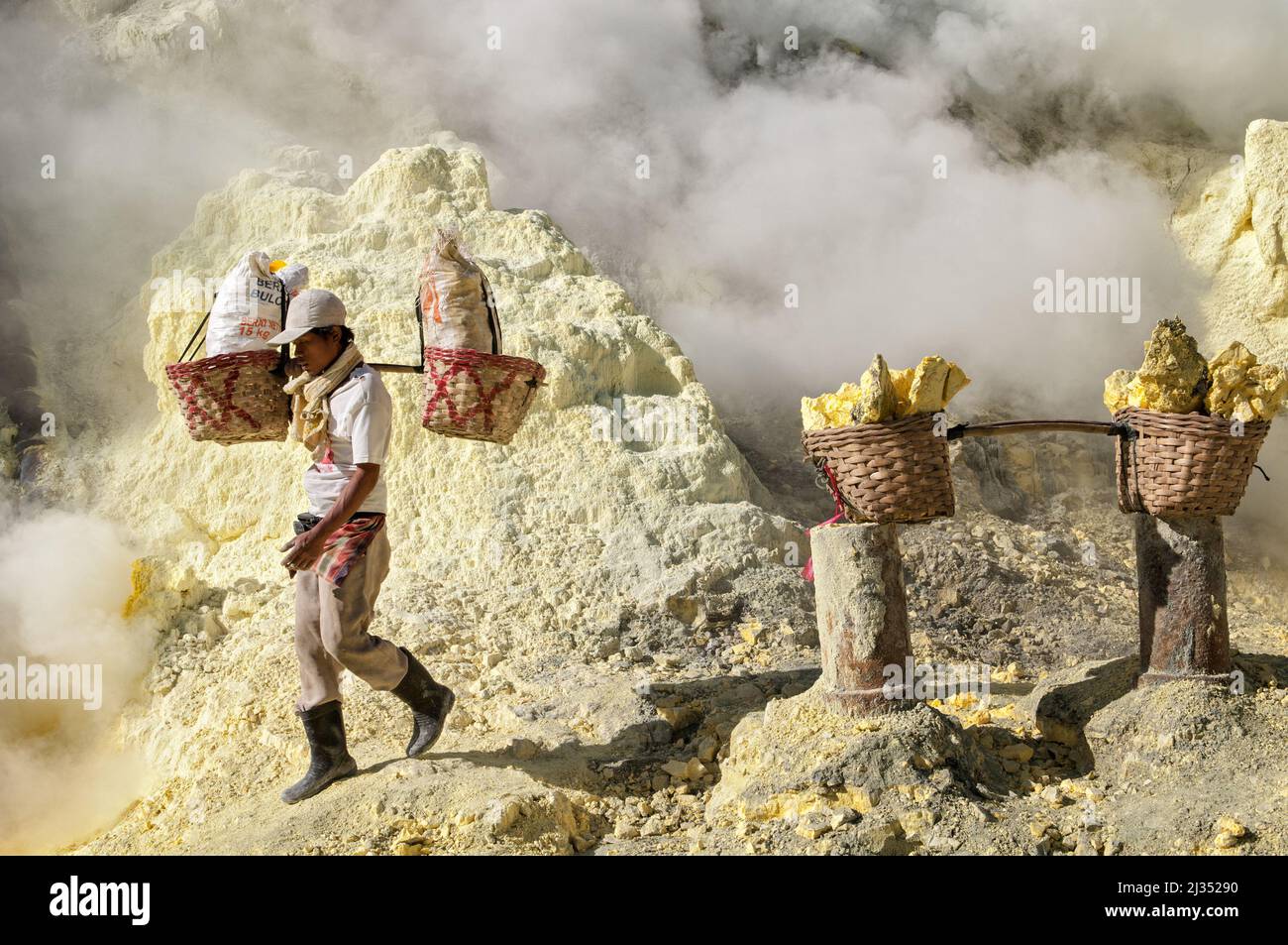 Sulfur miner carrying baskets inside the crater of Ijen volcano, Java Island, Indonesia Stock Photo