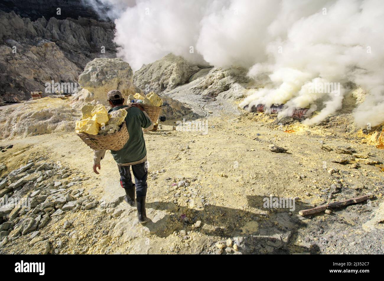 Miner carrying baskets with sulfur inside the crater of Ijen volcano, Java Island, Indonesia Stock Photo
