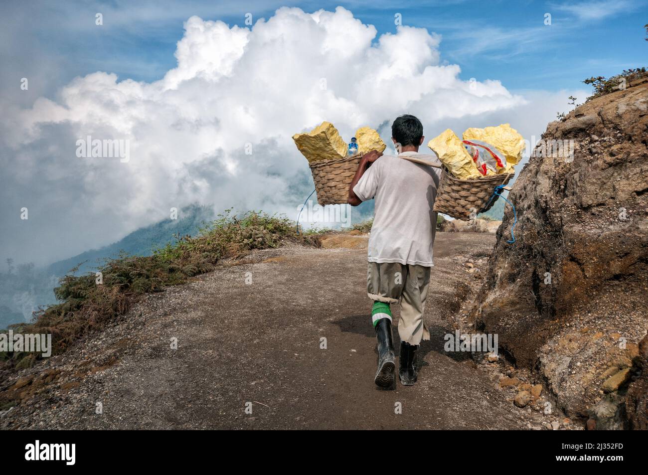 Porter carrying sulfur on a trail of Ijen volcano, Java Island, Indonesia Stock Photo