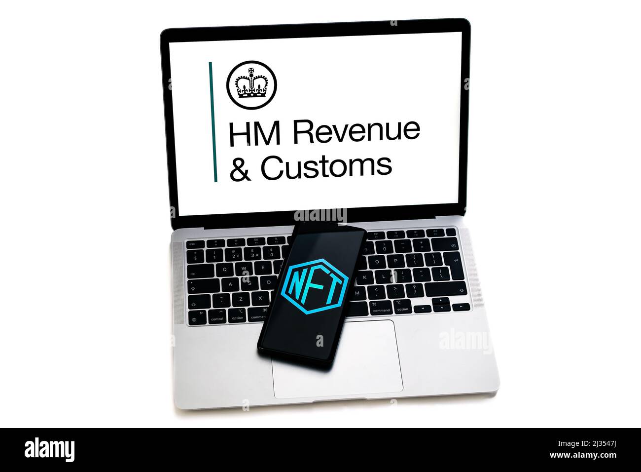 NFT logo seen on smartphone placed on laptop keyboard with HMRC logo. Selective focus. Concept. Stafford, United Kingdom, April 5, 2022 Stock Photo