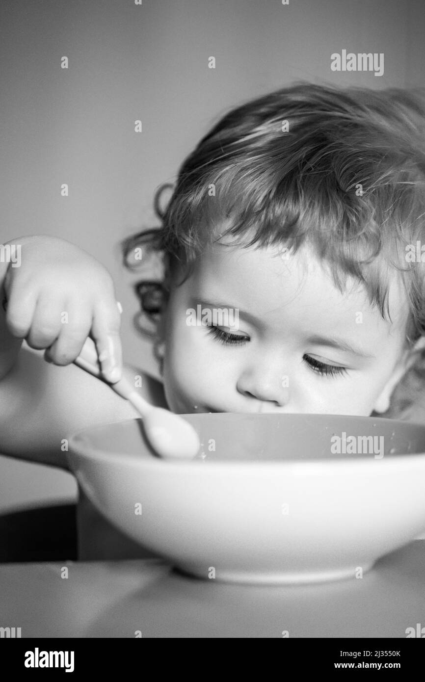 Kid baby eat soup in the kitchen with dishes and spoon Stock Photo - Alamy