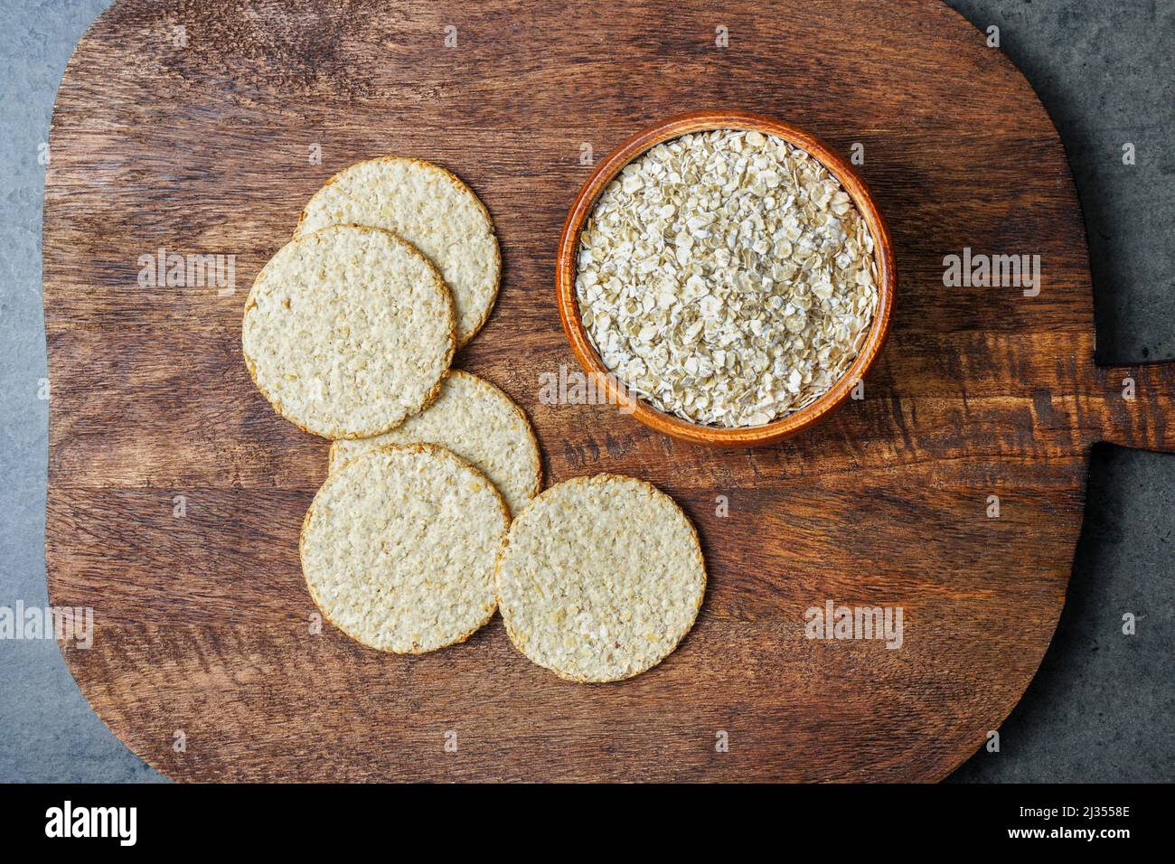 Healthy crackers made from oatmeal next to rolled oats. Stock Photo