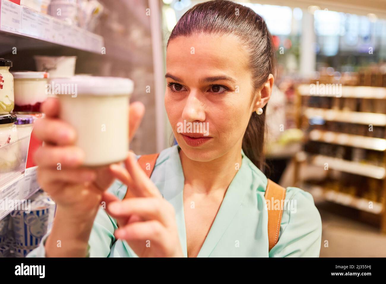 Woman as a critical consumer when shopping in the supermarket checks the shelf life of the product Stock Photo