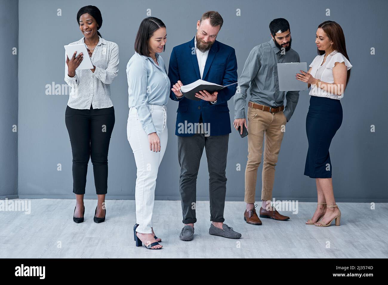 Building collaborative relationships and a cooperative work culture. Shot of a group of businesspeople working against a grey background. Stock Photo
