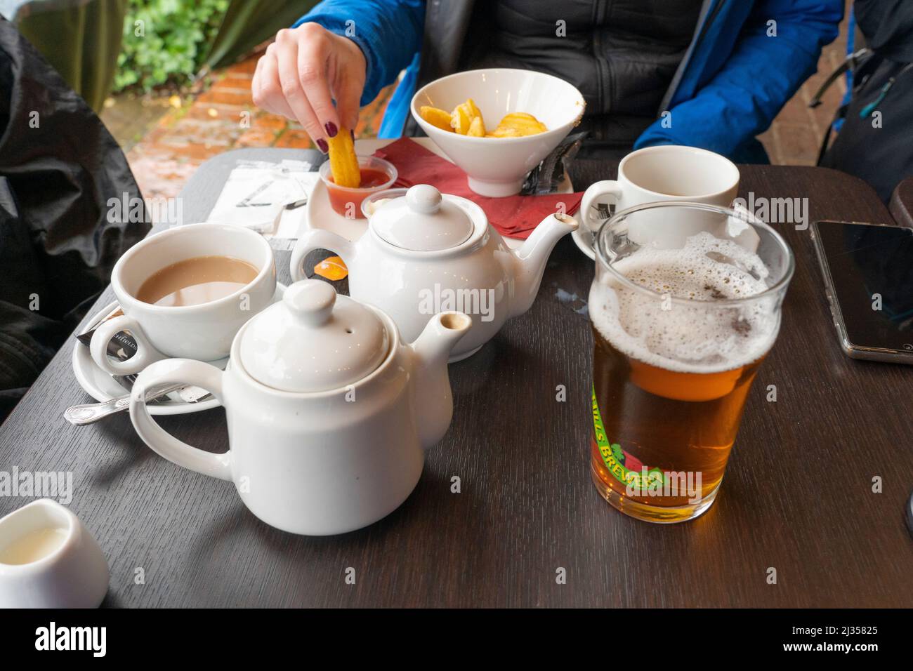 Hikers drinking tea and beers and eating chips trying to stay warm on an autumn Box Hill (Surrey) walk at the King William IV country pub. England Stock Photo