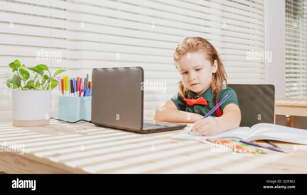 Cute schoolboy child does her homework with a tablet or laptop at home