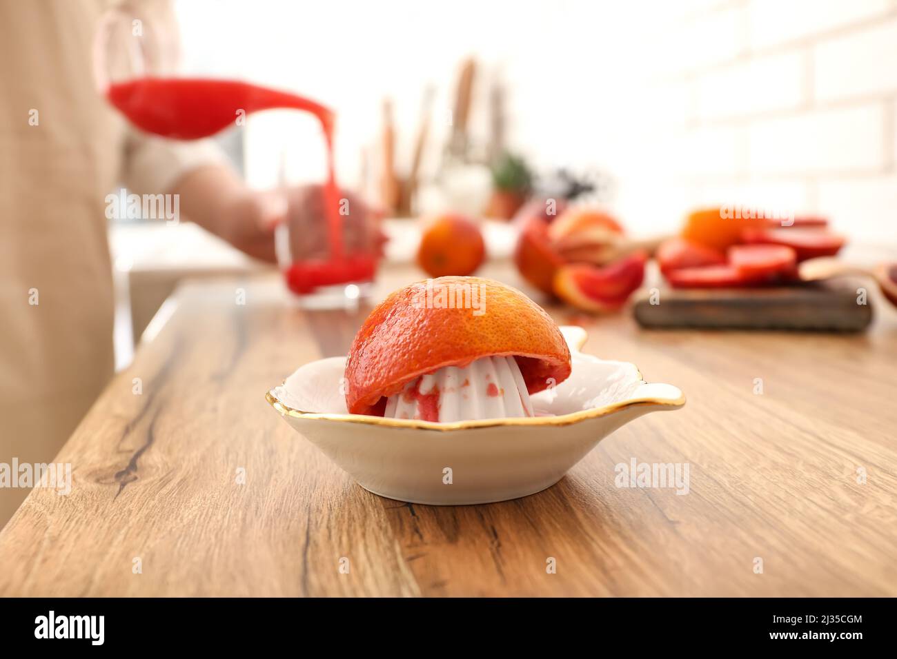 Ceramic juicer with orange on wooden table Stock Photo