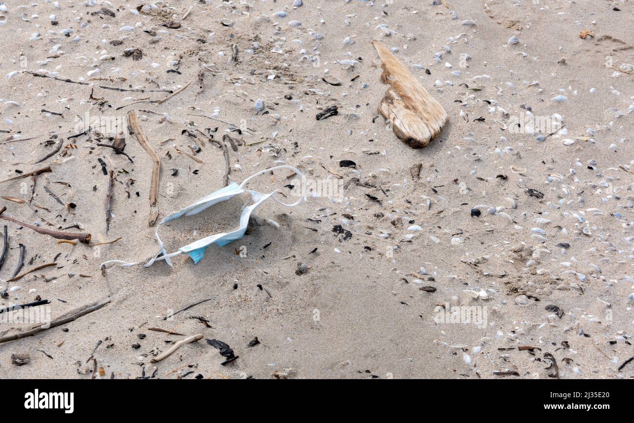 A sign of the covid times, a surgical mask lies discarded on a beach. Stock Photo