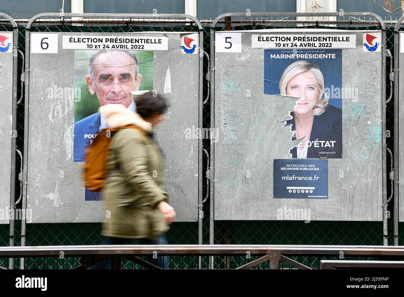 Paris, France, April 5, 2022, A pedestrian passes an official campaign poster of far-right candidate Eric Zemmour (Reconquete), and the one of Marine Le Pen (Rassemblement National) on an electoral billboard (sign). Presidential posters on their electoral boards. Illustration picture on April 5, 2022 in Paris, France. French voters head to the polls to vote on April, 10, 2022 for the first round of the presidential election, to elect their new president of the Republic. Photo by Victor Joly/ABACAPRESS.COM Stock Photo