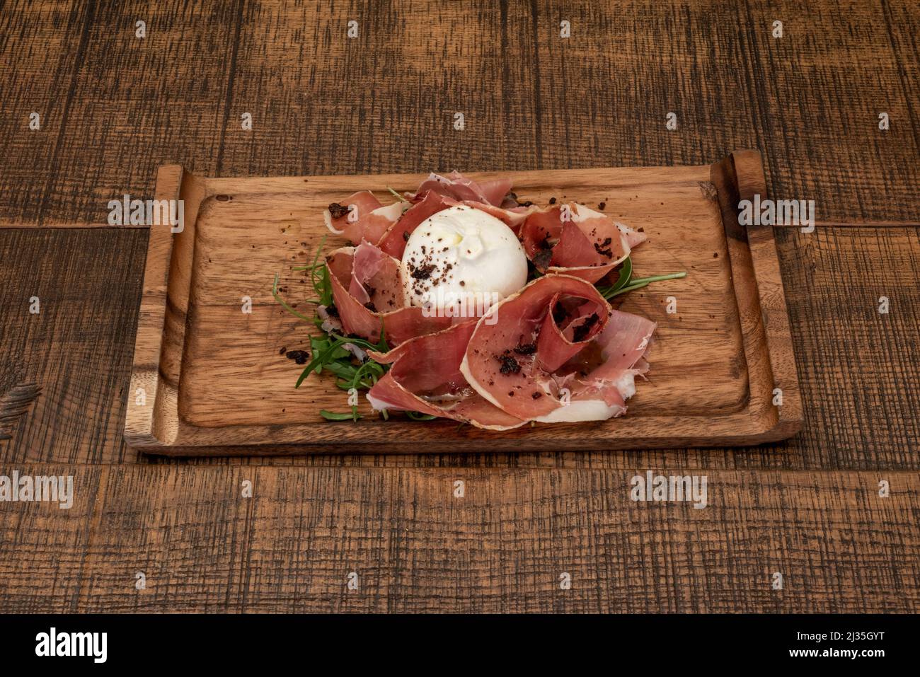 Typical Italian salad of fresh burrata cheese with arugula, ground