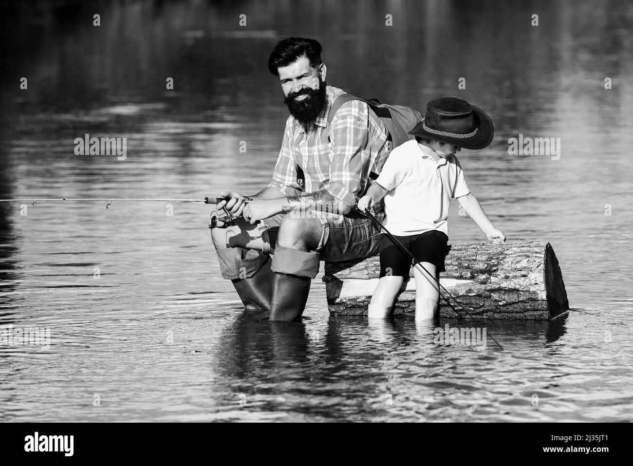 Father and boy son fishing together. His enjoys talking to father. Concept of a retirement age. Happy father and son fishing in river holding fishing Stock Photo