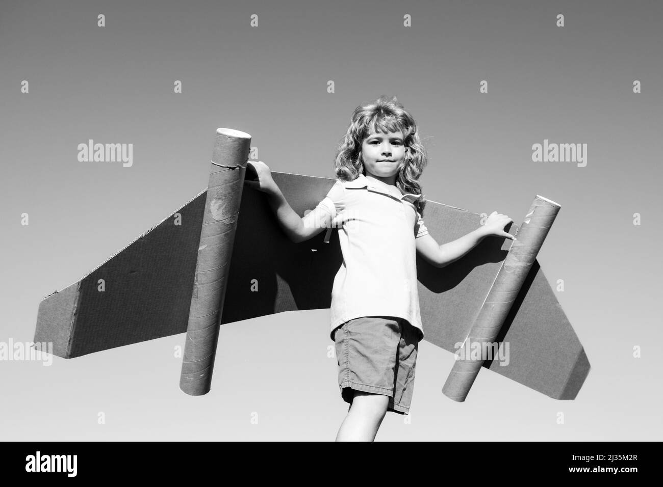 Happy child with paper wings against blue sky. Kid with toy jetpack ...