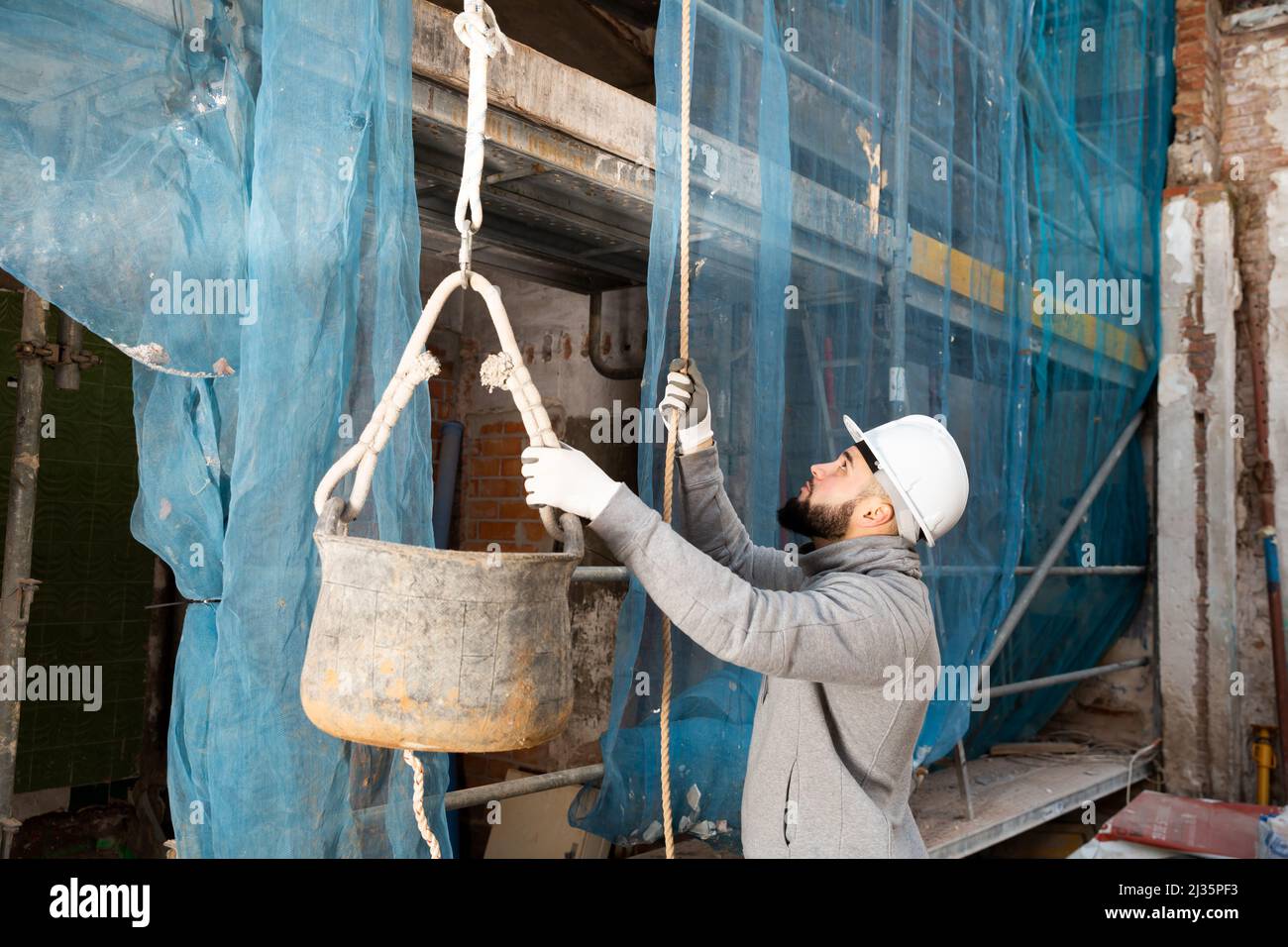 Worker lifting bucket with cement mortar Stock Photo Alamy