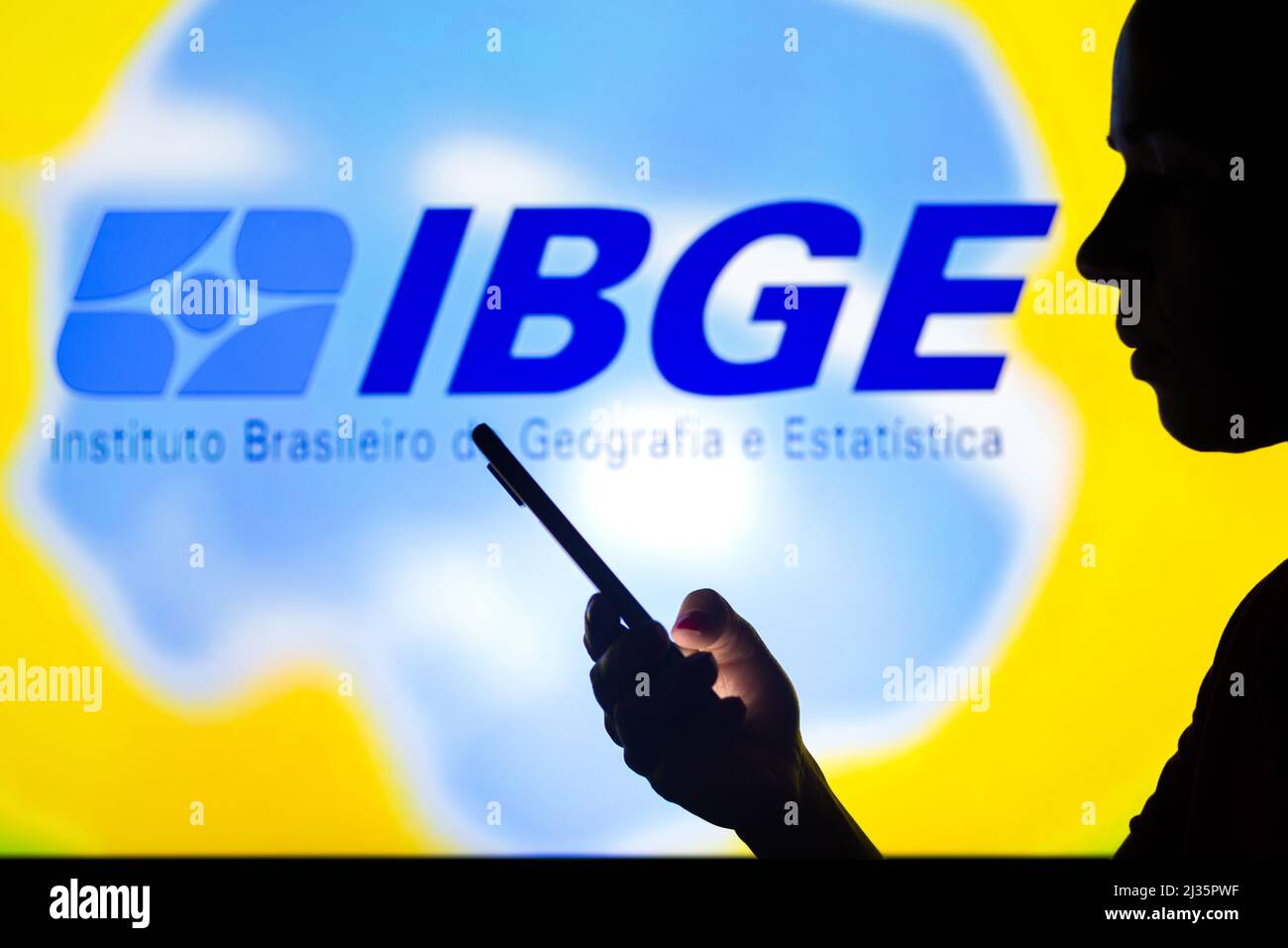 Brazil. 05th Apr, 2022. In this photo illustration, a woman's silhouette holds a smartphone with the IBGE (Brazilian Institute of Geography and Statistics) logo in the background. (Photo by Rafael Henrique/SOPA Images/Sipa USA) Credit: Sipa USA/Alamy Live News Stock Photo