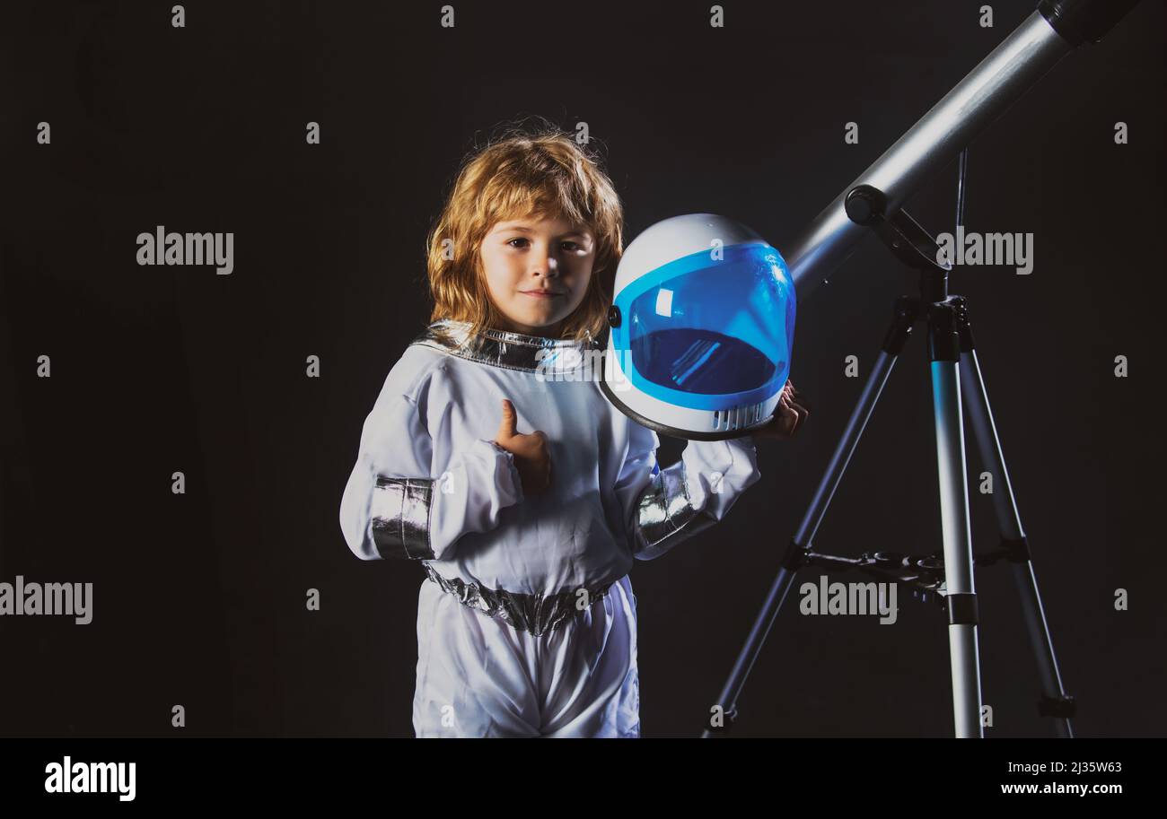 Child boy with a telescope is dressed in an astronaut