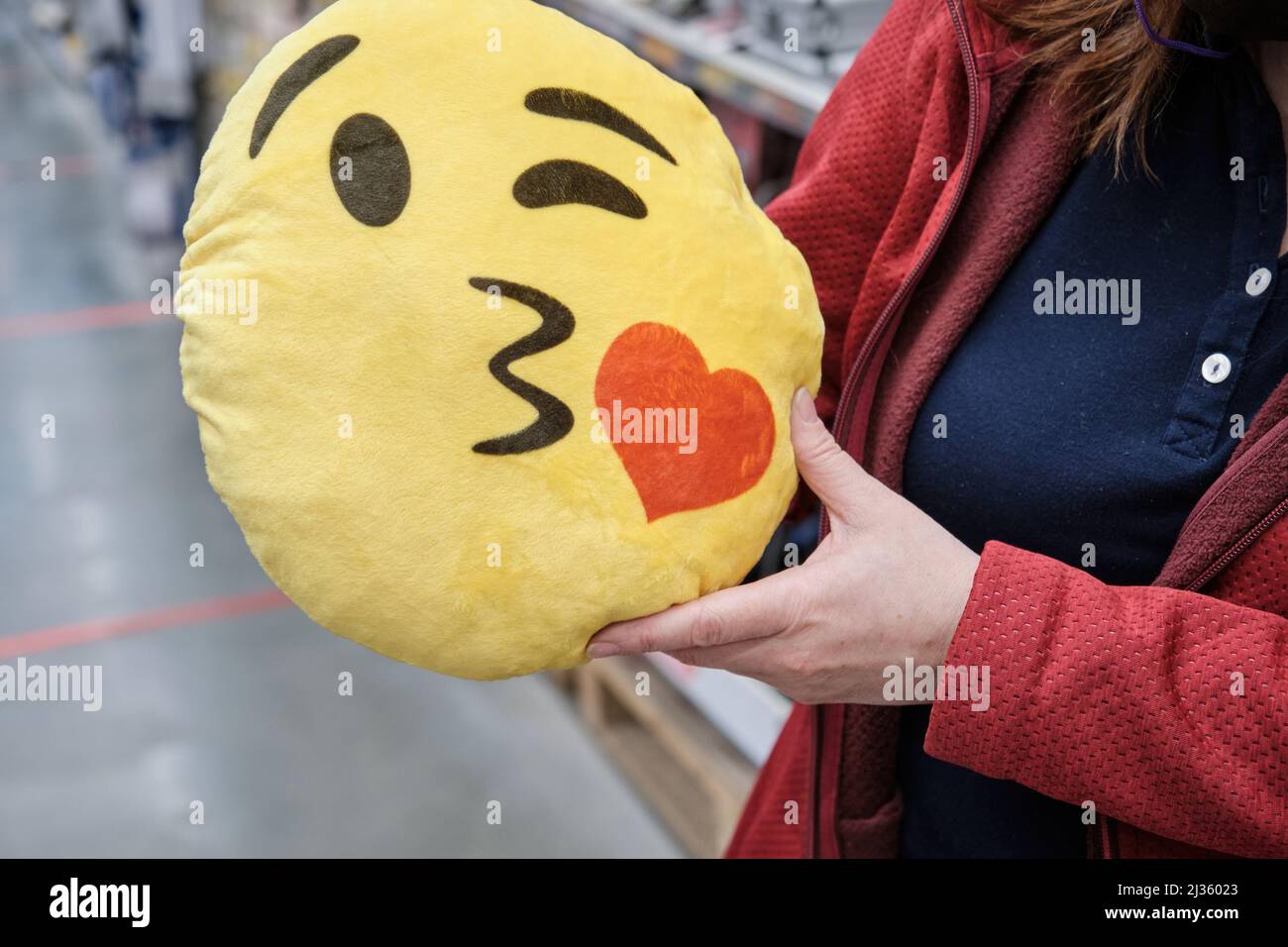Girl in store buys funny pillow in form of yellow smiley face for car seat Stock Photo