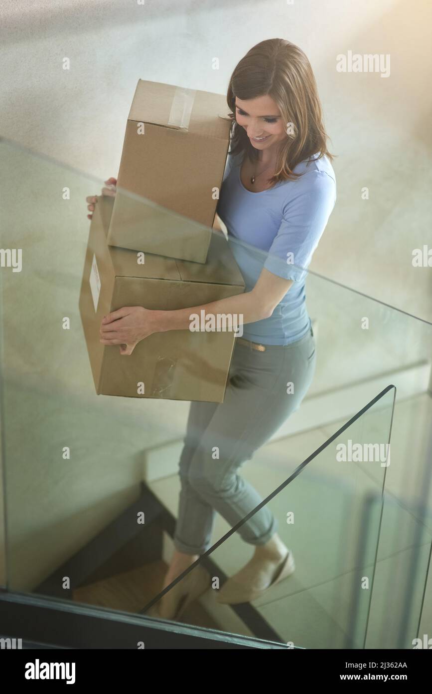 Making sure nothing gets left behind. Shot of a happy young woman carrying boxes while moving out of her house. Stock Photo