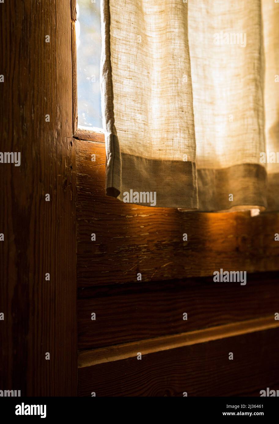 A curtain hanging over a window on a door with sunlight sneaking in between. Stock Photo
