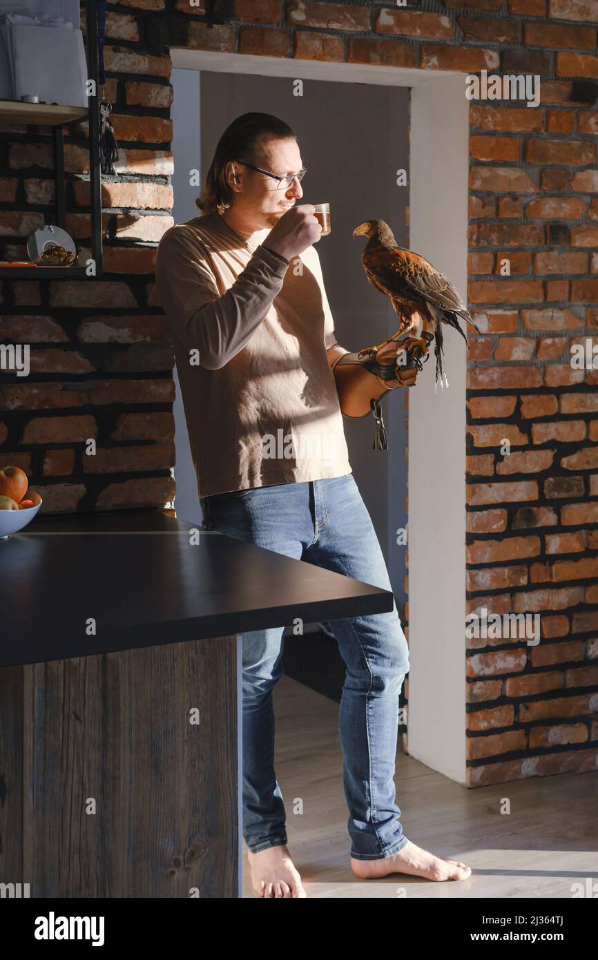 Man drinking coffee with wild bird at home on the kitchen. Eagle as pet. Unusual  animals at home. Human friendship. Taking care of buzzard, sunlight Stock  Photo - Alamy