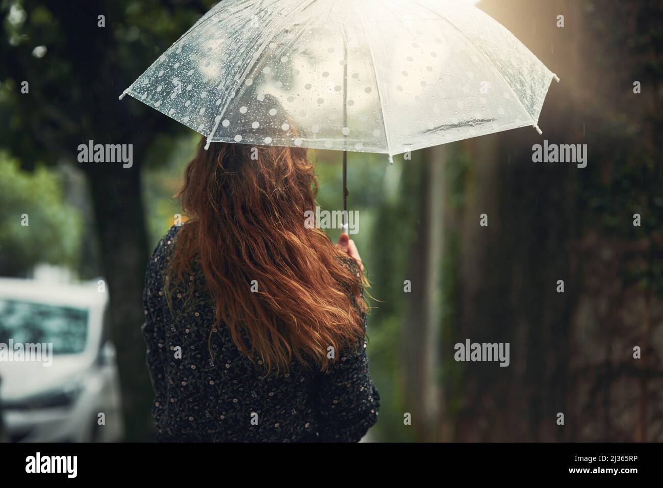 Let the rain wash away all the worries of yesterday. Rearview shot of an unrecognizable woman walking in the rain outside. Stock Photo