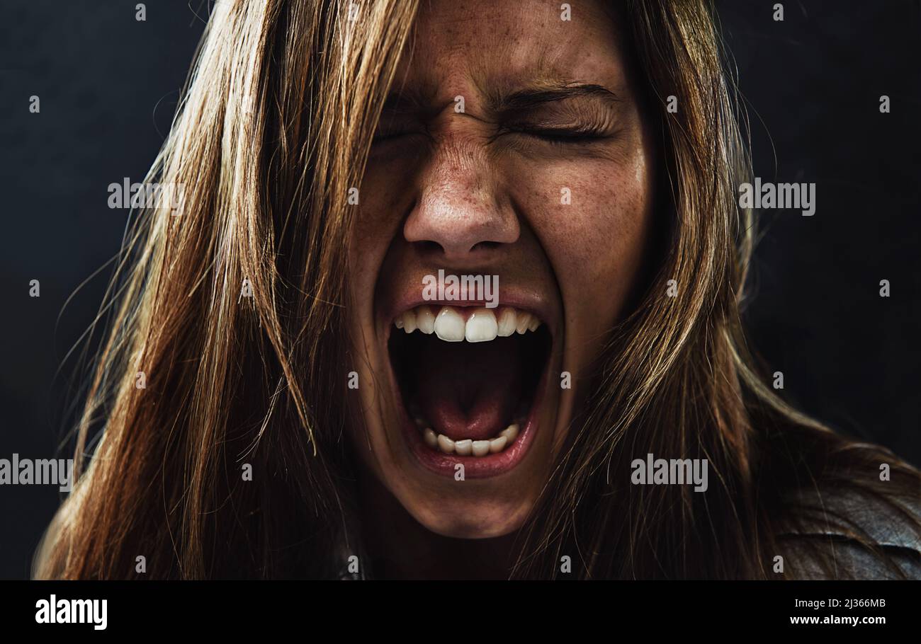 Shes reached the end of her rope. A young woman screaming uncontrollably while isolated on a black background. Stock Photo