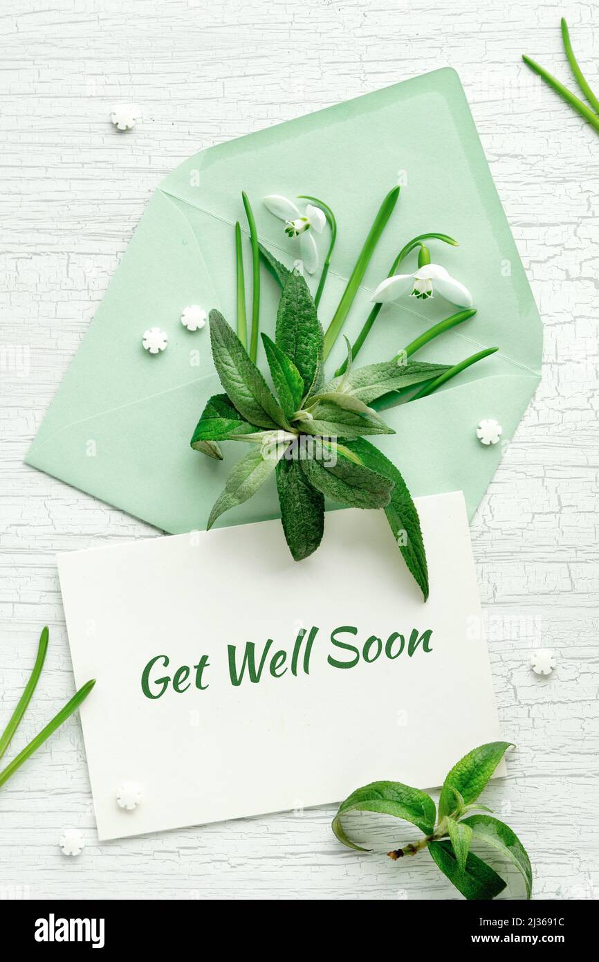 Card Get Well Soon. Spring decor in mint green, off white. Paper envelope with greeting card. White snowdrop flowers and sugar sprinkles. Stock Photo