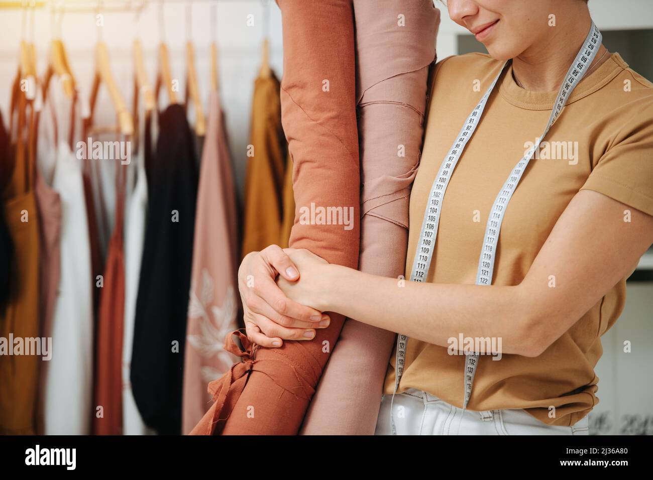 Cropped image of a seamstress hugging rolls of fabric. Half face ...
