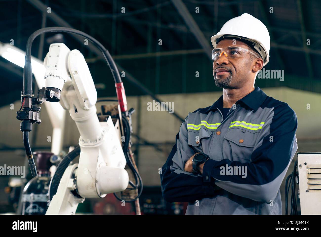 African American factory worker working with adept robotic arm in a