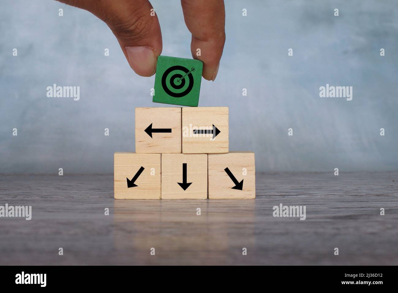 Wooden cubes with target icon and arrow pointing different direction. Organize a team, set a goal. Stock Photo