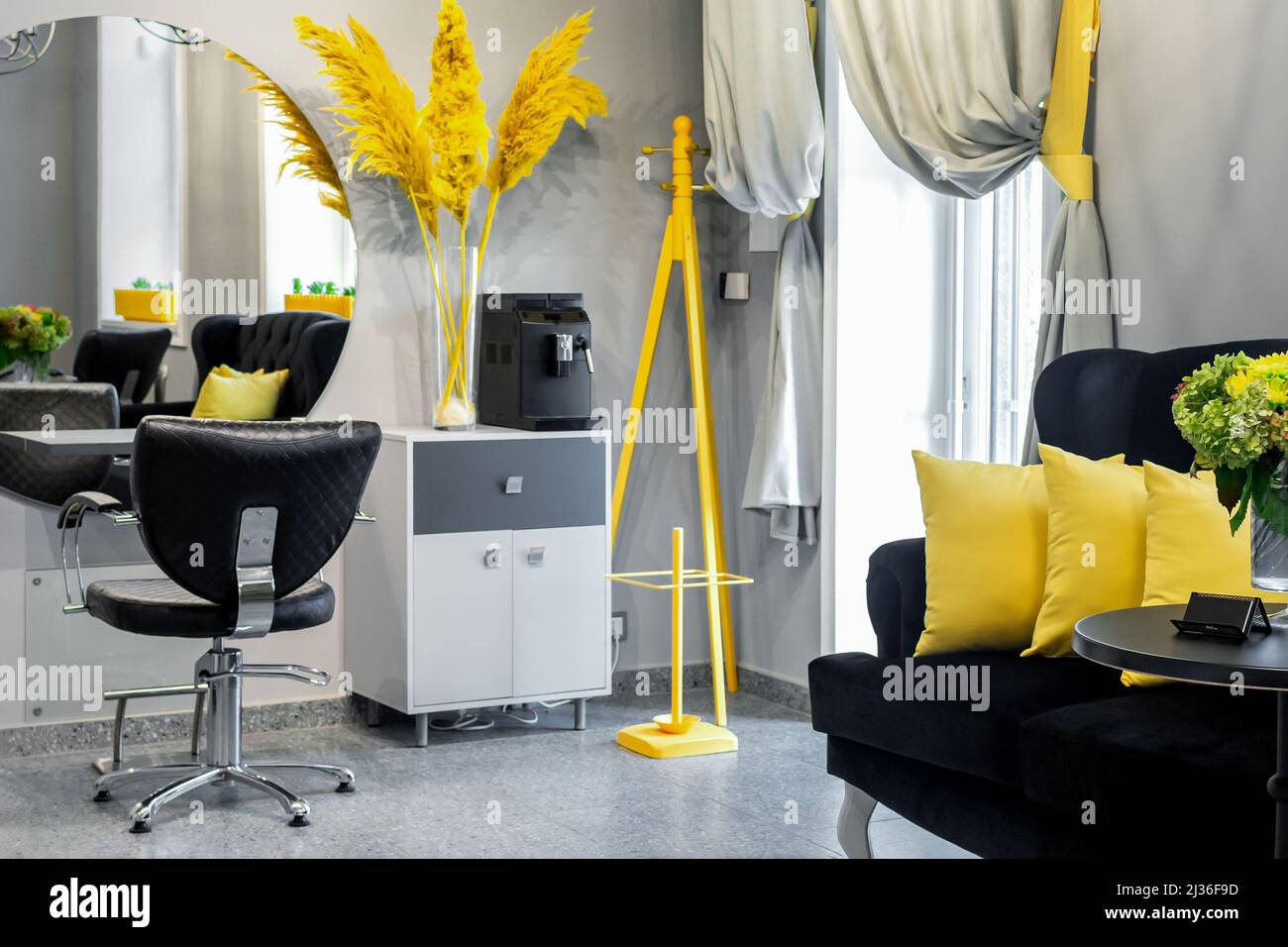 Modern small bright hair and beauty salon in black and yellow colors with  gray walls and floor and black sofa with yellow cushions Stock Photo - Alamy