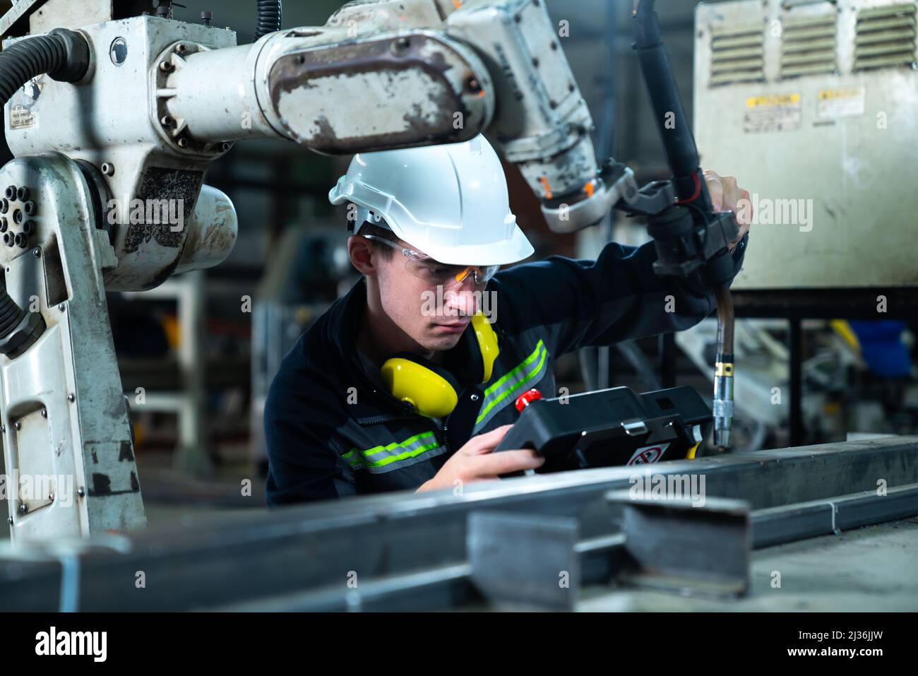 Young factory worker working with adept robotic arm in a