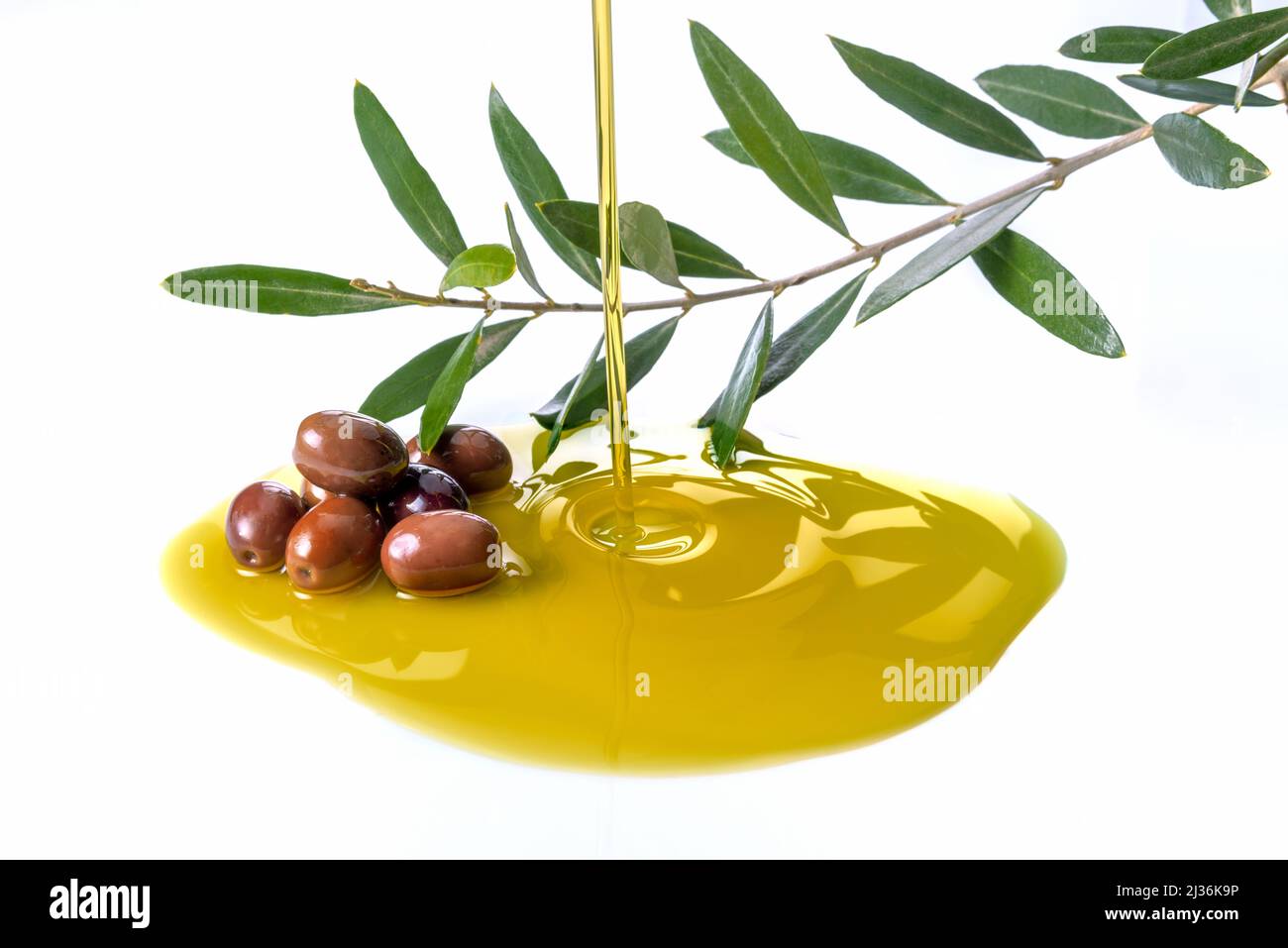 Pouring olive oil with olives and branch with olive leaves isolated on white Stock Photo