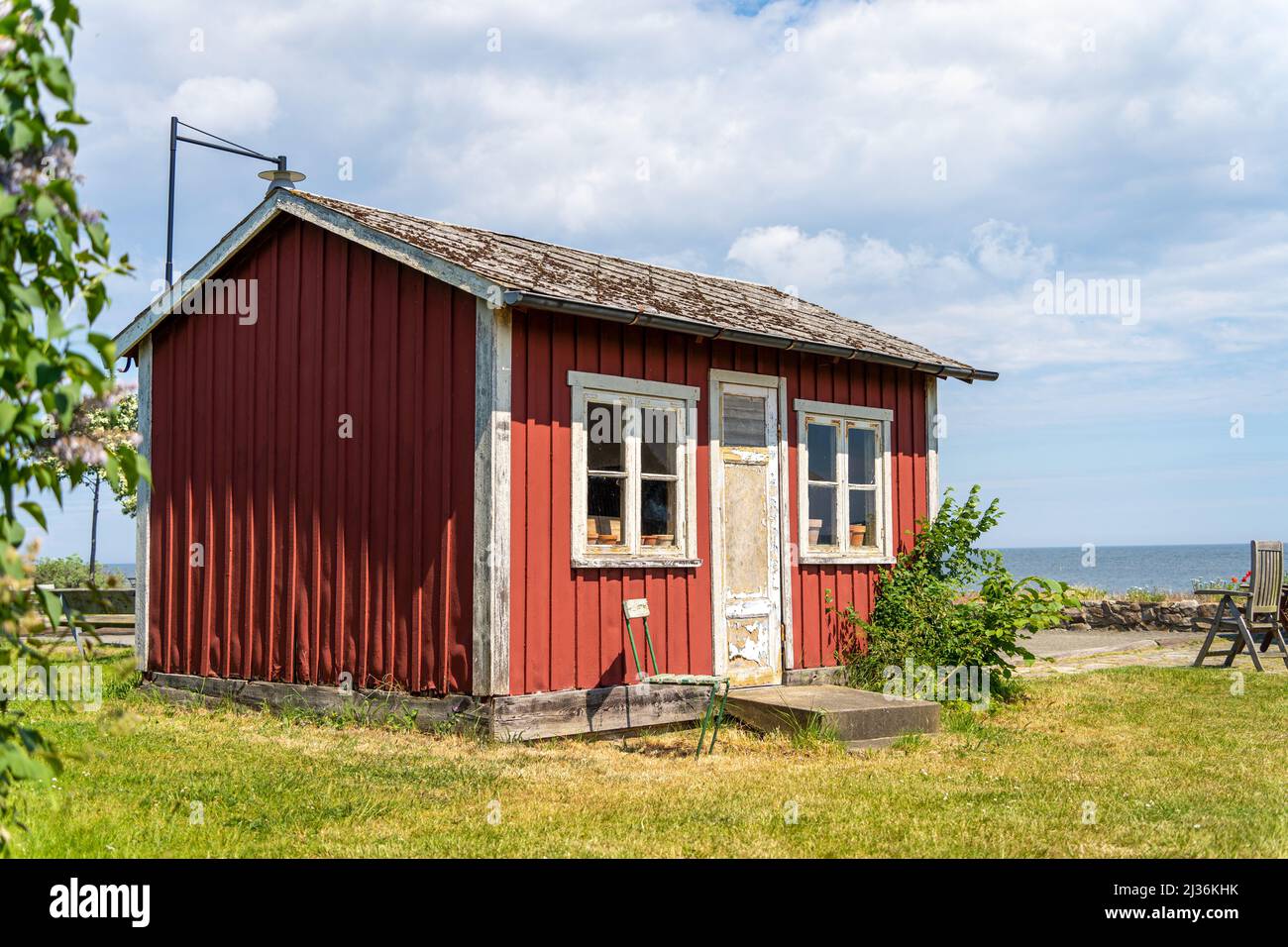 Red wooden fishing scandinavian buildings over the fjord. Black and green roofs. The coast of central Sweden. Stock Photo