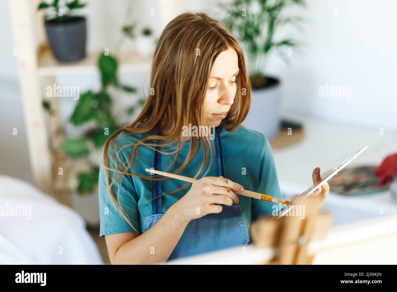 Fine art school. Closeup of artist portrait ,hands holding wooden palette, mixing acrylic paint with brush.Artist woman with paint palette.Hand with brush painting.  Stock Photo