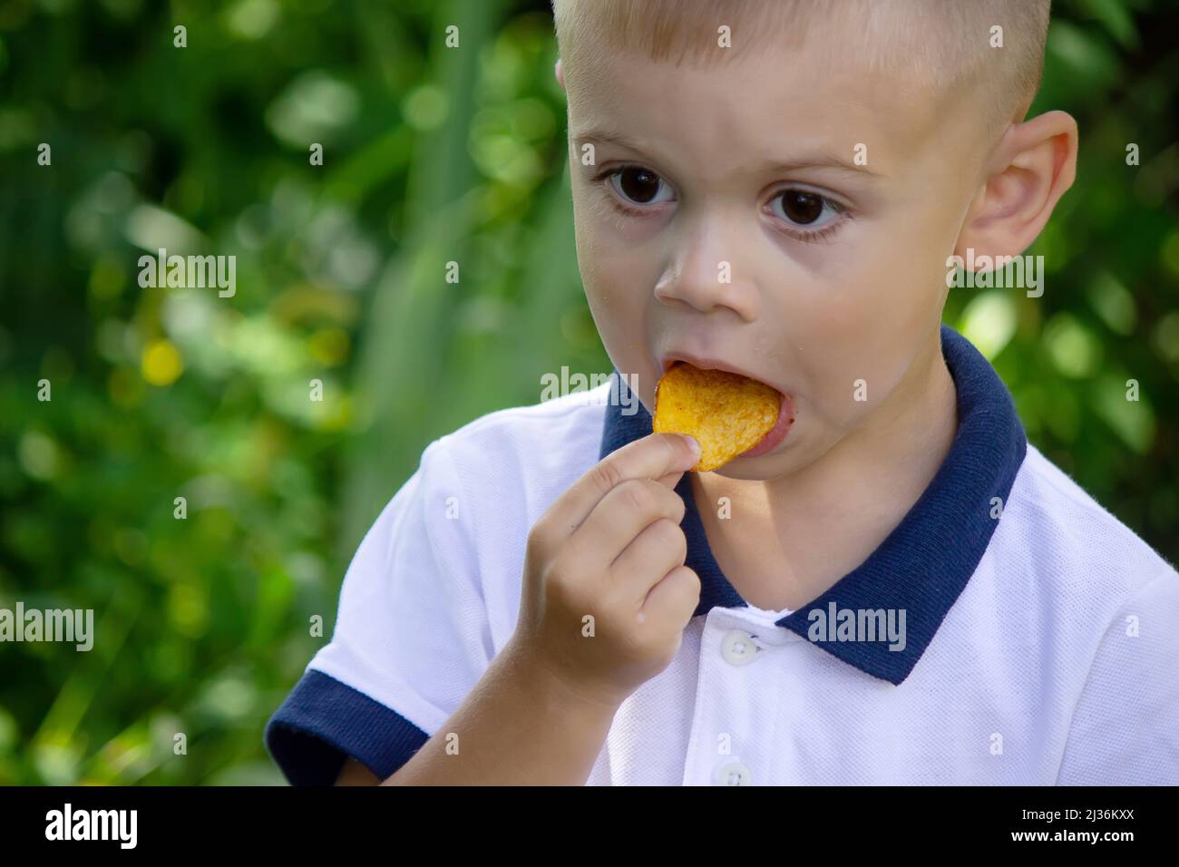 potato chips in the boy's hand, the boy eats the chips. selective focus Stock Photo