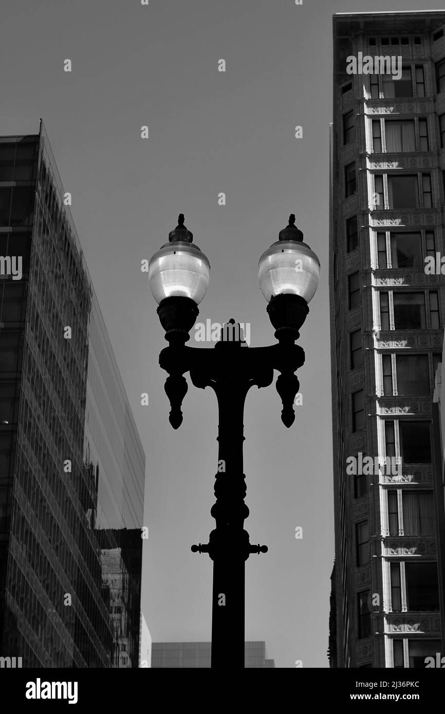 Beautiful cast iron street light glowing in the evening dusk in black