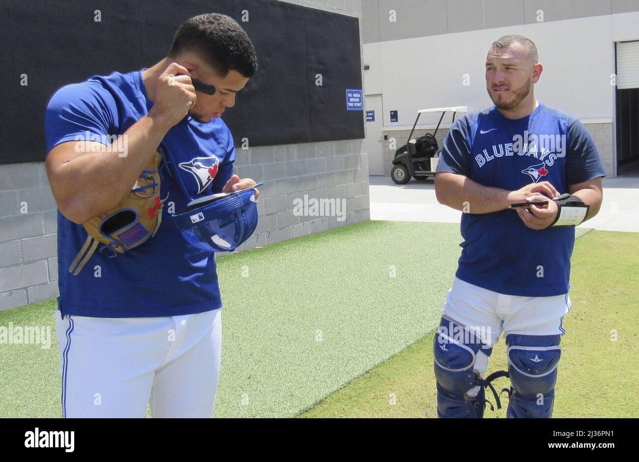 Toronto Blue Jays pitcher Jose Berrios (L) tests a device used to call