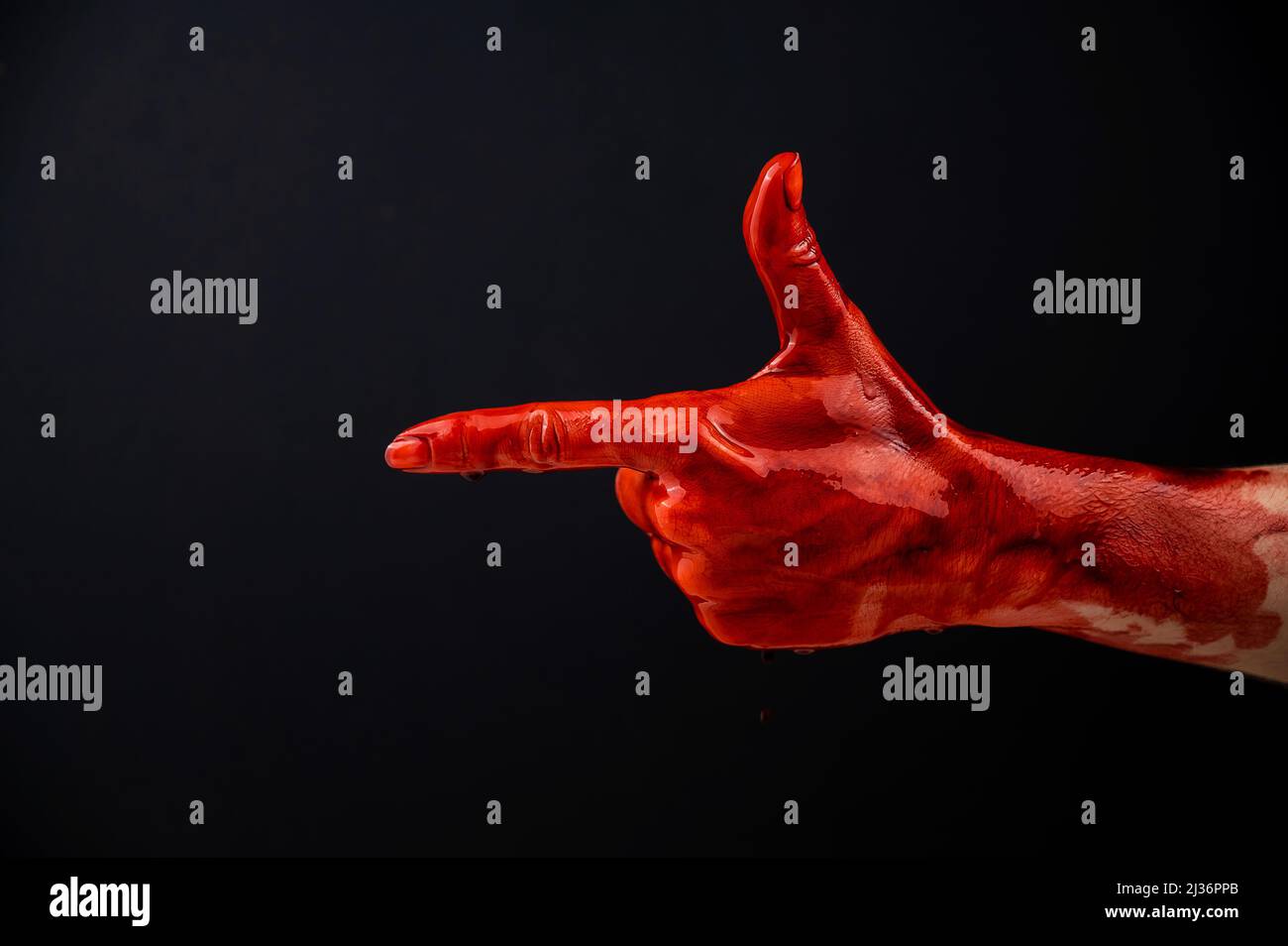 Woman's hand in blood shows a gesture of a gun on a black background.  Stock Photo