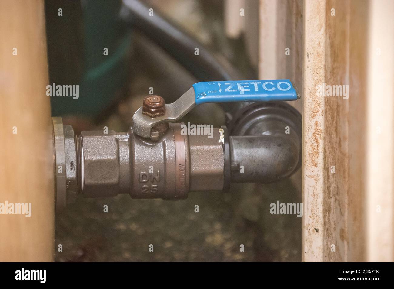 Press-fit brass ball-valve tap with lever handle. Outlet at bottom of 5000 litre poly rainwater tank in garden in Queensland, Australia. Stock Photo