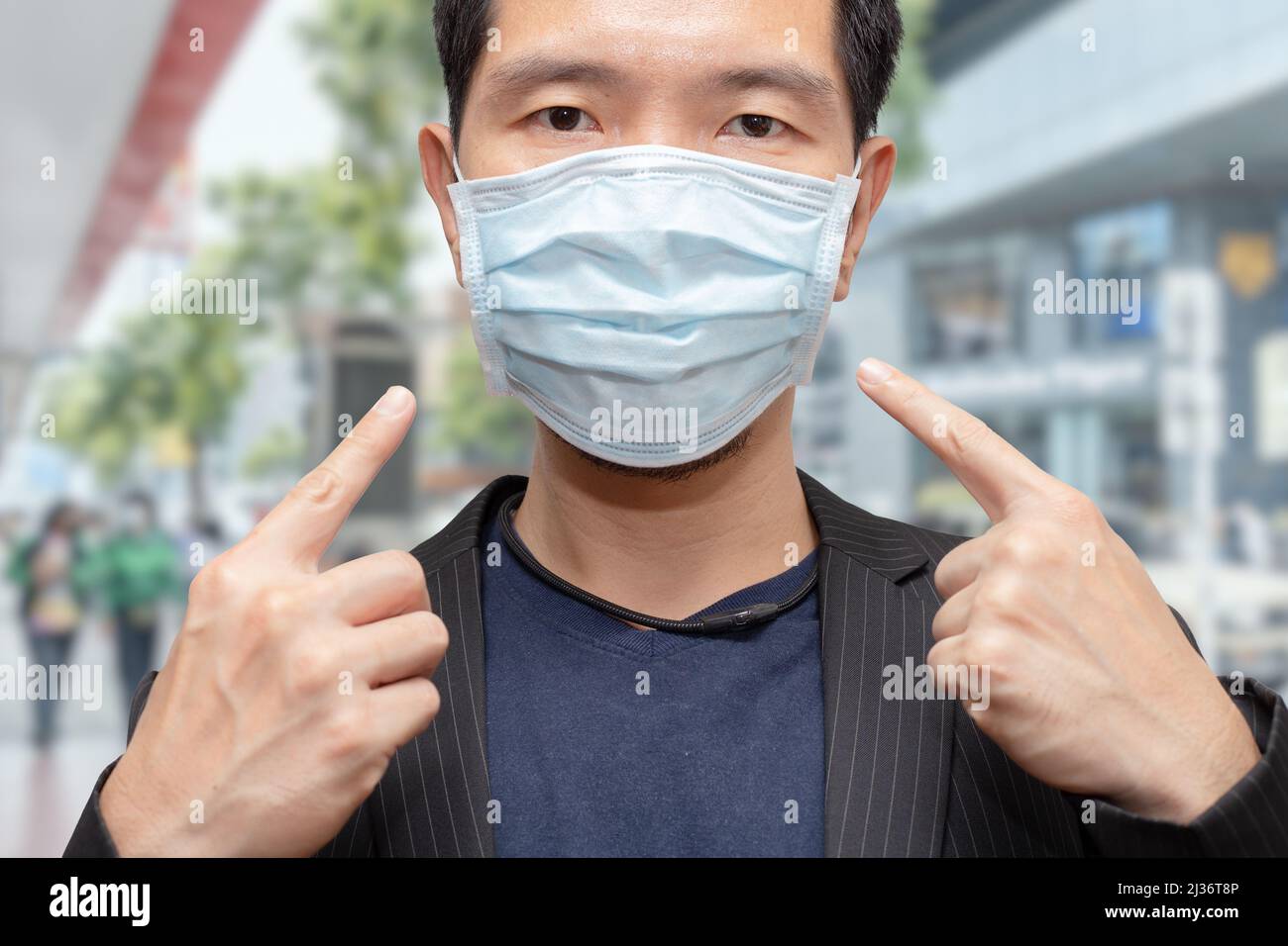 Asian Male wearing face mask in public area outdoor for prevent Covid-19 and air pollution. Stock Photo