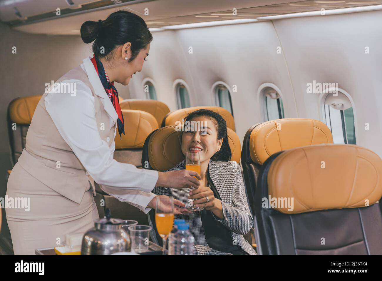 Air hostess flight cabin crew serve food and drink service passenger during travel on board. Stock Photo