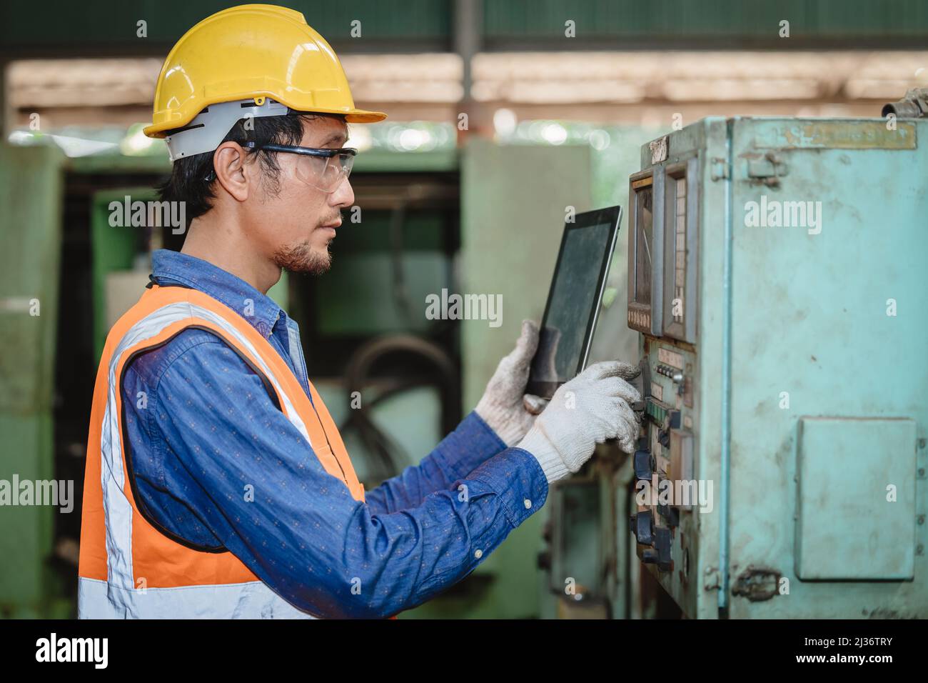 Engineer worker program setup CNC machine in metal industry factory with tablet technology. Stock Photo