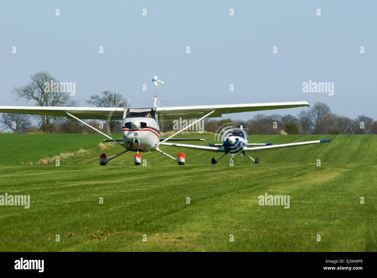 Cessna 172 and British Aerospace Bulldog planes taxiing to start the air race at Great Oakley, UK, with one plane having taken off and turning corner Stock Photo